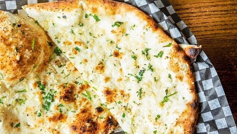 Garlic Naan freshly baked in the clay tandoor and brushed with garlic butter at Angeethi Flame Indian Restaurant Cedar Park TX